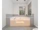Jetted soaking tub is surrounded by tile with window view of outdoors at 2600 Oakmeade Dr, Charlotte, NC 28270