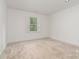Minimalist bedroom featuring neutral carpet flooring, bright white walls, and natural light at 2600 Oakmeade Dr, Charlotte, NC 28270