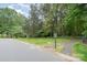 Manicured front yard with lush landscaping, a sign, and a tree-lined street enhance the curb appeal of this home at 2600 Oakmeade Dr, Charlotte, NC 28270