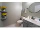 Charming half bath features a gray vanity, round mirror, and decorative shelves with floral accents at 3412 Summerfield Ridge Ln, Matthews, NC 28105