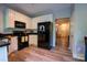 Well-lit kitchen with white cabinets, black appliances, and wood-look floors at 3412 Summerfield Ridge Ln, Matthews, NC 28105