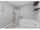 Bathroom featuring a soaking tub and glass-enclosed shower, accented by modern shelves at 3744 Leela Palace Way, Fort Mill, SC 29708