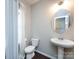 Half bathroom features a pedestal sink, round mirror, and toilet with tiled floor and natural light from the window at 4012 Martele Dr, Mint Hill, NC 28227