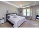 Bright bedroom featuring a tray ceiling, pendant lighting, a comfy bed, and large windows at 4012 Martele Dr, Mint Hill, NC 28227