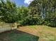 Backyard with a wooden deck, lush trees, and a blend of grass and soil, providing a relaxing outdoor retreat at 521 Ellingsworth Ln, Charlotte, NC 28214