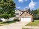 Charming two-story home featuring stone accents, red shutters, a lush lawn, and a driveway leading to a two car garage at 521 Ellingsworth Ln, Charlotte, NC 28214
