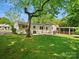 Spacious backyard with lush green grass, mature trees, and a view of the home at 5219 Farmbrook Dr, Charlotte, NC 28210