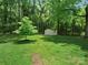 Spacious backyard with storage shed surrounded by mature trees and green grass at 5219 Farmbrook Dr, Charlotte, NC 28210