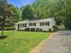 Charming exterior featuring a well-kept lawn and gravel driveway, complemented by mature trees offering shade and privacy at 5219 Farmbrook Dr, Charlotte, NC 28210