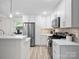 Bright kitchen featuring white cabinets, stainless steel appliances, and modern lighting fixtures over a breakfast bar at 5219 Farmbrook Dr, Charlotte, NC 28210