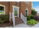 A charming brick home's front entrance with white railing and well-manicured landscaping at 7700 Ninth Fairway Ln, Mint Hill, NC 28227