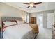 Bright main bedroom featuring a tufted headboard, ceiling fan, and an ensuite bathroom at 7700 Ninth Fairway Ln, Mint Hill, NC 28227