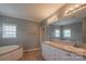 Bathroom featuring double sinks, a large mirror, and a soaking tub with natural light at 7740 Freeze Rd, Kannapolis, NC 28081