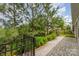 This paved backyard walkway features mature trees, landscaping, and a black metal fence at 8210 Festival Way, Charlotte, NC 28215