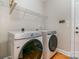 Functional laundry room featuring a modern washer and dryer, storage shelf, and wood-look flooring at 9588 Marquette Nw St, Concord, NC 28027