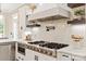 Close-up of kitchen highlights featuring stainless steel range and pot filler, custom vent hood and tile backsplash at 1001 Medinah Ct, Waxhaw, NC 28173