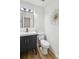 Modern half bathroom featuring wood floors, a black vanity, and a contemporary mirror enhancing its appeal at 11216 Carmel Chace Dr, Charlotte, NC 28226