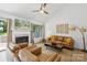 Cozy living room featuring a white fireplace, tan sofas, ceiling fan and a large window at 11216 Carmel Chace Dr, Charlotte, NC 28226
