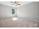 Neutral bedroom with large window letting in natural light, carpet flooring, and ceiling fan at 11931 The Ramble Dr, Huntersville, NC 28078