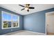 Blue bedroom with natural light from window with backyard view, ceiling fan, and white trim at 11931 The Ramble Dr, Huntersville, NC 28078