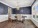Elegant dining room with dark blue walls, white trim, a wooden table with tufted chairs and chandelier at 11931 The Ramble Dr, Huntersville, NC 28078