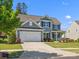 Charming two-story home with a well-manicured lawn, featuring a two-car garage and inviting front porch at 11931 The Ramble Dr, Huntersville, NC 28078