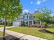 Beautiful gray two-story home featuring an attached two-car garage, a charming front porch and manicured lawn at 11931 The Ramble Dr, Huntersville, NC 28078