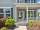 Covered front porch entrance showcasing gray siding, white columns, and green landscaping, with a partial view of the street at 11931 The Ramble Dr, Huntersville, NC 28078