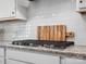 Close-up of a stovetop with a backsplash, showcasing the kitchen's sleek design and modern appliances at 11931 The Ramble Dr, Huntersville, NC 28078