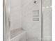 Modern walk-in shower featuring marble-style tiles, a built-in bench, and convenient recessed shelving at 11931 The Ramble Dr, Huntersville, NC 28078