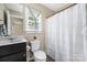Compact bathroom features a dark wood vanity, toilet, and shower with white curtain at 12224 Huntersville Concord Rd, Huntersville, NC 28078