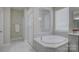 Bathroom featuring a bathtub, a glass enclosed shower, and natural lighting at 15108 Montage Ln, Charlotte, NC 28278