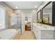 Bathroom featuring a glass-enclosed shower, soaking tub, and double vanity with a view into bedroom at 16216 Woolwine Rd, Charlotte, NC 28278