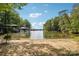 Sandy beach leading to a calm lake with boat docks, framed by lush green trees on a sunny day at 16427 Cozy Cove Rd, Charlotte, NC 28278