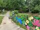 Charming park pathway lined with colorful flower garden, leading to a wooden bridge and lush greenery at 2115 Mecklenburg Ave, Charlotte, NC 28205