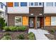 Exterior of townhomes featuring brick and gray siding, accented by wood elements, lush landscaping, and unit numbers at 2123 Bryant Park Dr, Charlotte, NC 28208