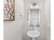 A stylish powder room featuring a pedestal sink, modern faucet, statement mirror, and a decorative pineapple artwork at 2123 Bryant Park Dr, Charlotte, NC 28208
