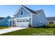 A charming blue two-story home with an attached two-car garage and well-manicured lawn at 122 Tillery Ln # 701P, Mount Gilead, NC 27306