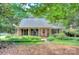 Quaint single-story brick home featuring mature landscaping and a cozy front porch at 2235 Ramblewood Ln, Charlotte, NC 28210
