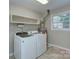 Functional laundry room with modern washer, dryer, shelving, and window at 2235 Ramblewood Ln, Charlotte, NC 28210
