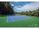 Well-maintained tennis court with vibrant blue surface, surrounded by green landscaping, ideal for tennis enthusiasts at 2235 Ramblewood Ln, Charlotte, NC 28210