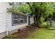 View of the back exterior featuring white siding and black trimmed windows, partially obscured by trees at 2622 Hemphill St, Charlotte, NC 28208