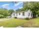 Exterior showcasing the white siding, accompanied by a lush green lawn and mature trees at 2622 Hemphill St, Charlotte, NC 28208