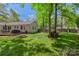 Lush green backyard with a wooden deck, fire pit, wood storage, and mature trees offering privacy and charm at 301 Deer Creek Dr, Matthews, NC 28105