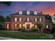 Stately brick home with dormers and manicured lawn at twilight at 3314 Leamington Ln, Charlotte, NC 28226
