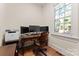 Functional home office with a wooden desk, three monitors, and natural light from a window at 3314 Leamington Ln, Charlotte, NC 28226