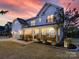 Stunning two-story home with a covered porch, stone accents, professional landscaping and a colorful sunset at 405 Winding Oaks Se Ln, Concord, NC 28025