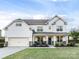 Charming two-story home with a well-manicured lawn, stone accents, and a welcoming front porch at 405 Winding Oaks Se Ln, Concord, NC 28025