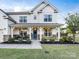 Charming two-story home featuring a welcoming front porch with stone accents and manicured landscaping at 405 Winding Oaks Se Ln, Concord, NC 28025