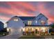 Beautiful two-story home with white siding, stone accents, covered porch and a vibrant sunset backdrop at 405 Winding Oaks Se Ln, Concord, NC 28025